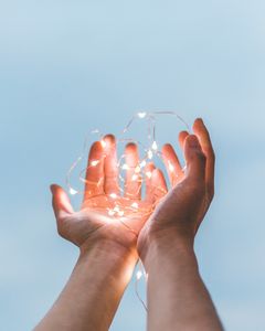 2 Hände halten eine brennende Lichterkette in der Hand