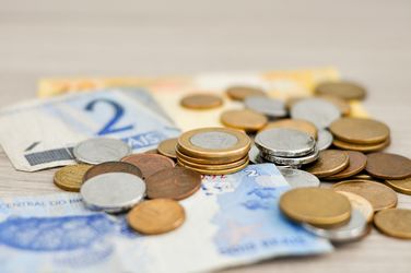 viele verschiedene Geldscheine und Münzen liegen durcheinander verteilt auf einem Tisch.