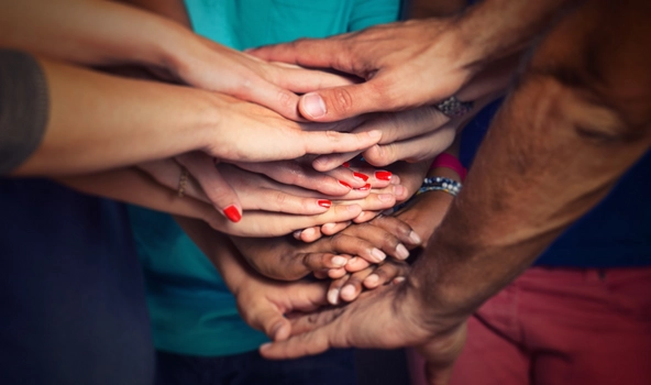 Viele Hände mit unterschiedlicher Hautfarbe liegen aufeinander.