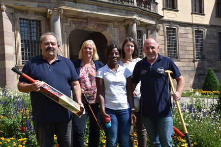 Sportcoaches stehen mit Cricket-Schlägern vor dem Stadtschloss in Fulda.