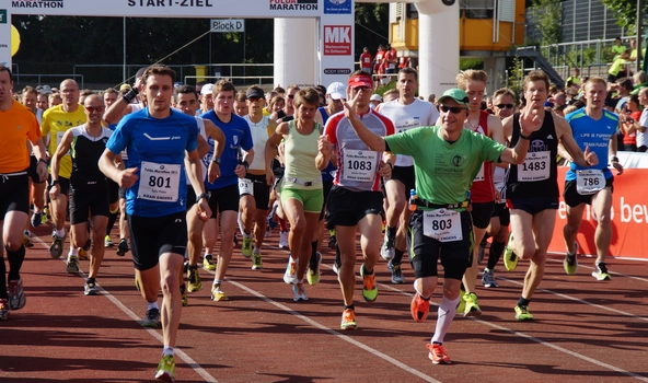 Viele Menschen laufen auf der Sportbahn einen Marathon.