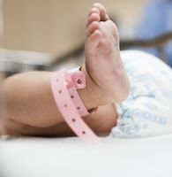 Fuß eines Babys. Es trägt ein Fußband für Neugeborene.